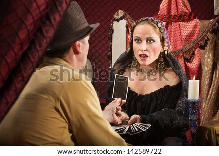 Shocked European fortune teller looking at tarot card