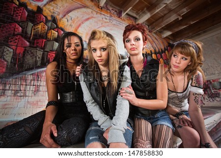 Sad group of young women sitting together in garage