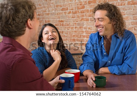 Laughing friends with coffee mugs in a restaurant