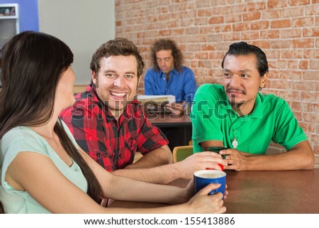 Asian man drinking coffee with Caucasian friends in cafe
