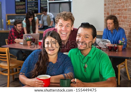 Two men and woman laughing in a cafe