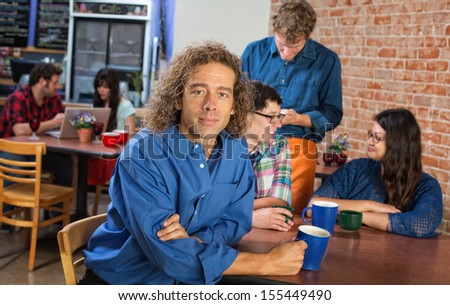 Handsome European male in blue shirt with friends in cafe