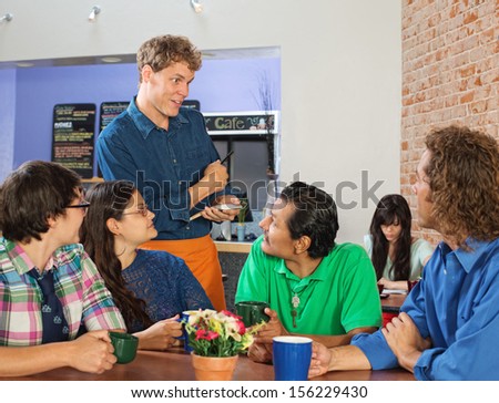 Friendly server taking orders from people in cafe