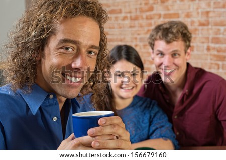 Smiling man with coffee and friends sitting together