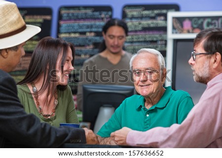 Cheerful older male with group of friends in cafe