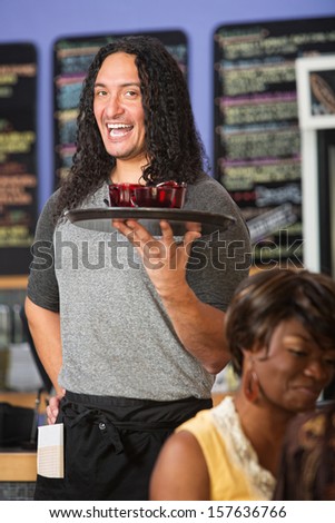 Happy Native American cafe owner serving drinks to customers