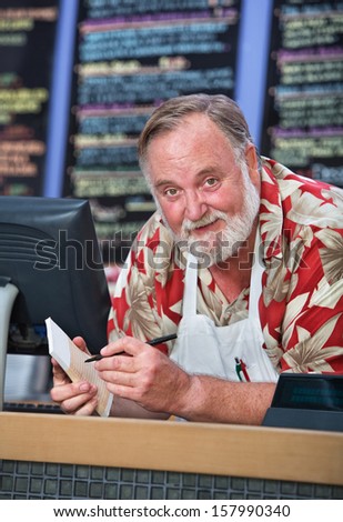 Grinning man in beard and mustache working at a cafe