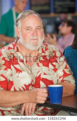 Grinning mature man sitting in cafe with coffee