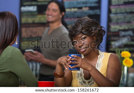 Grinning African woman with coffee mug in cafe