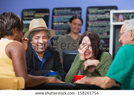 Diverse group of adults joking in a coffee house