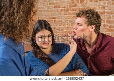 Annoyed woman being kissed by European male