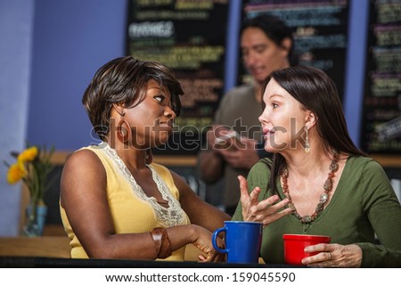 African and European women in a coffee house talking