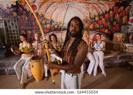 Capoeira teacher with dreadlocks and students playing music