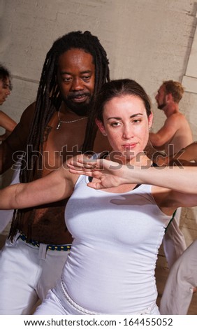 Cheerful capoeira master working with female student indoors