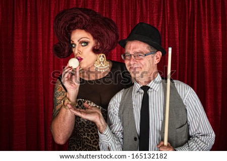 Cross dressing man kissing cue ball with smiling friend