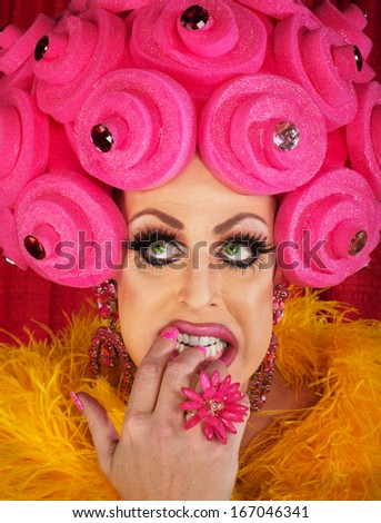 Nervous drag queen in pink wig biting nails