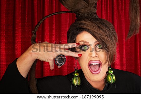 Laughing Caucasian drag queen in theater with hand near face