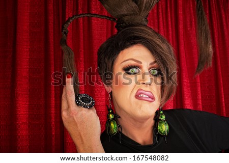 Annoyed European drag queen pulling on ponytails