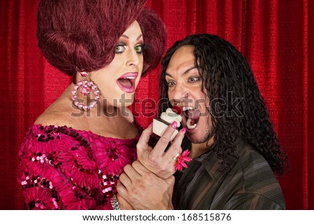 Tall drag queen and hungry man eating cupcakes