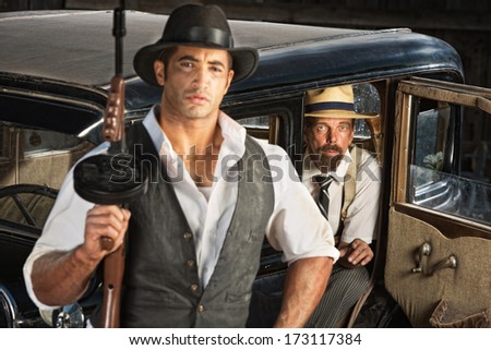 Cute 1920s gangster with submachine gun and partner in car