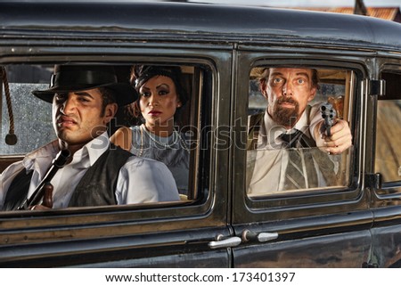 Group of 1920s vintage gangsters in drive by shooting