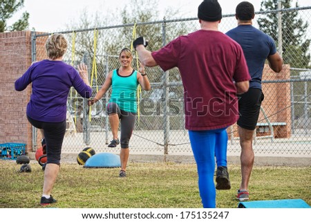 Active adults with instructor performing boot camp exercises