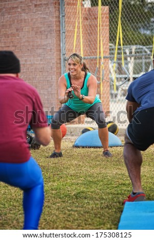 Cheerful boot camp fitness instructor squatting