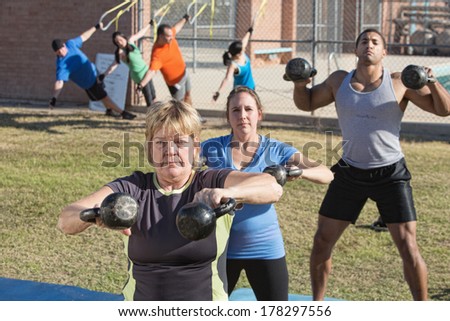 Mature woman and group exercising in outdoor boot camp fitness class