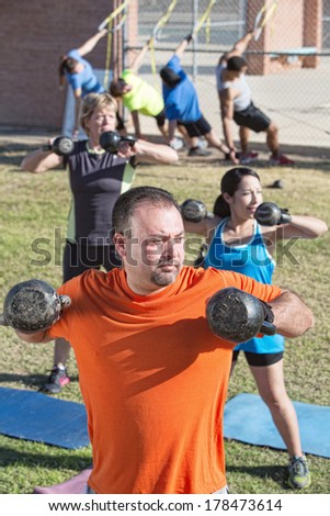 Fit mature adults exercising with weights in boot camp fitness class