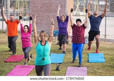 Mature adult boot camp fitness class stretching outdoors