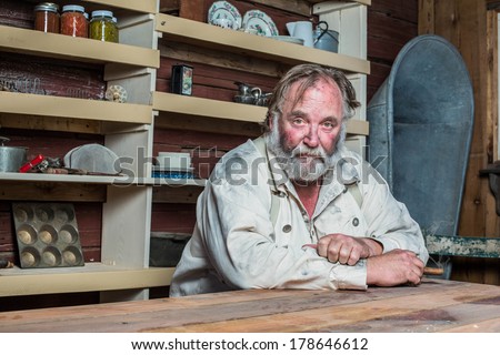 Solemn western man looks towards you as he sits at table