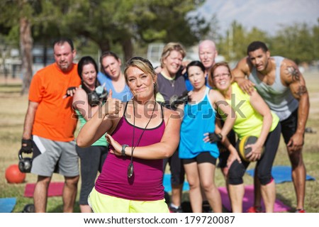 Boot camp fitness instructor with group and thumbs up