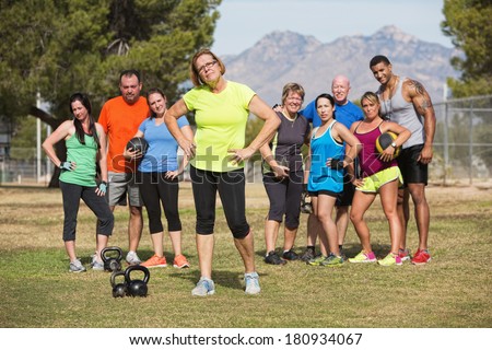 Serious mature woman with boot camp fitness class outdoors