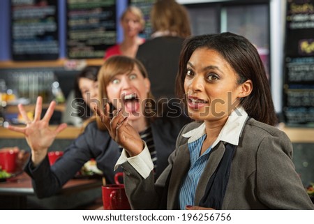Business woman in cafe with person making fun of her