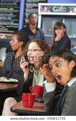 Obnoxious woman talking loudly on cell phone in cafe