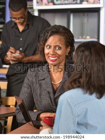 Happy Black business woman with friend in restaurant