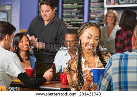 Cute young African woman with braids with friend in cafe