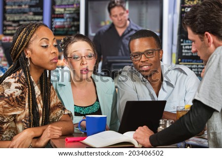 Diverse group of four male and female students in cafe