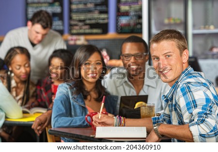 Handsome Caucasian student doing homework with friends