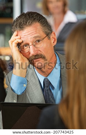 Sad businessman listening to woman in cafe