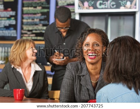 Cute laughing mature business woman with friend in cafe