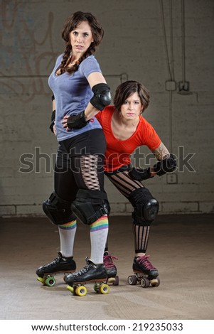 Pair of tough Caucasian female roller derby skaters