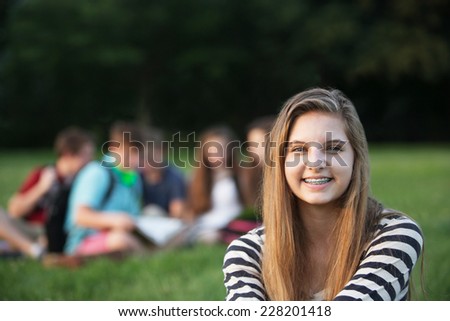 Cute smiling teenage girl with braces sitting outdoors
