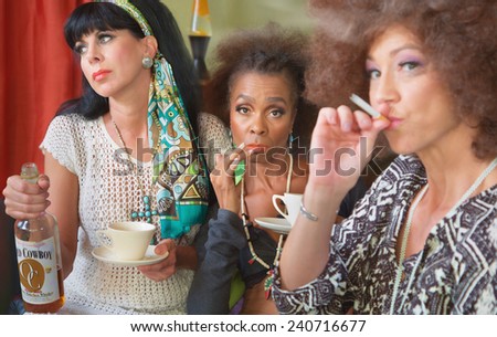 Group of three female adults drinking and smoking