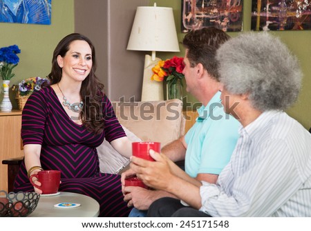 Smiling expecting surrogate mother with mature male friends