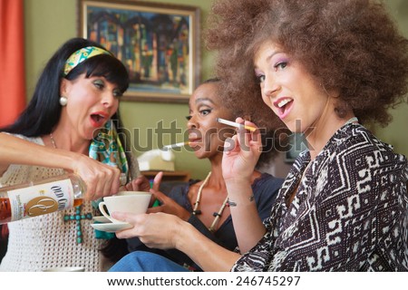 Laughing women smoking cigarettes and drinking alcohol