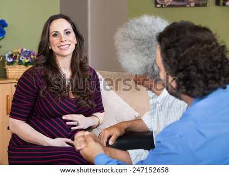 Smiling surrogate mother sitting with homosexual parents