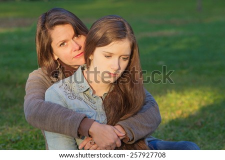 Concerned European mother holding depressed daughter outdoors