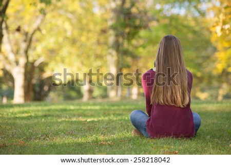 Unidentifiable woman sitting cross legged on grass