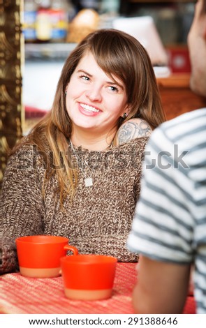 Cute woman smiling at friend in restaurant